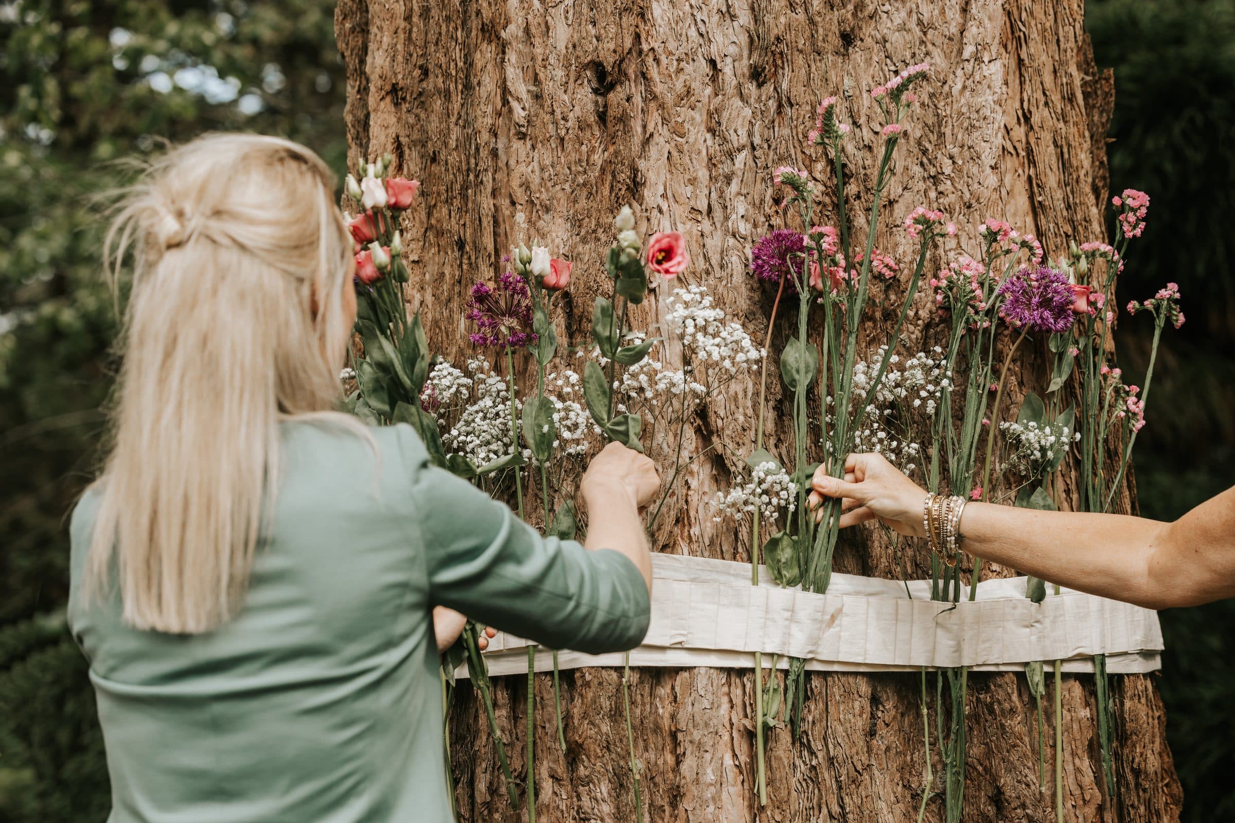 Bloemen worden in een band rond een boomstam geschikt