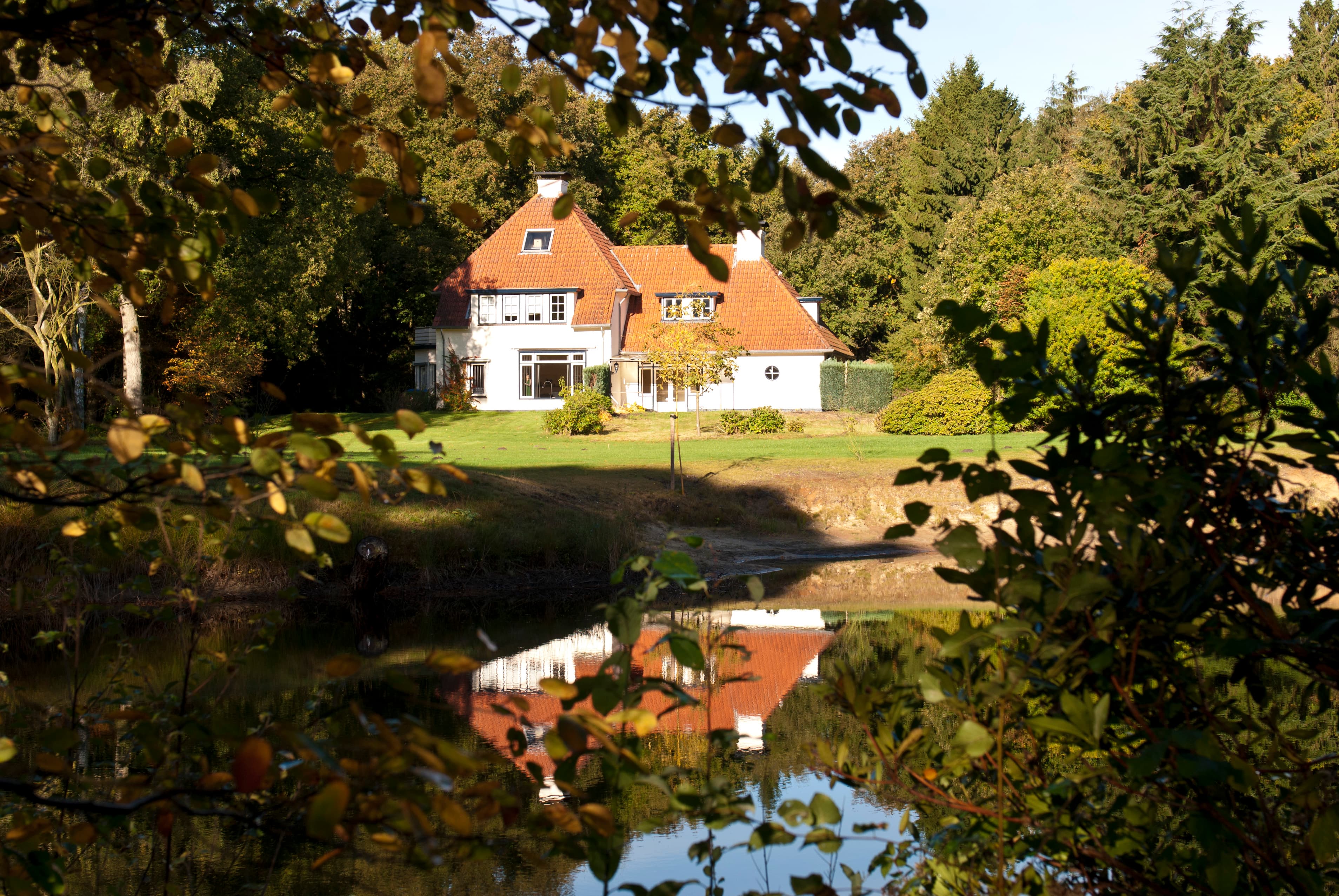 Het Boshuisje gespiegeld in de vijver tussen herfstbomen