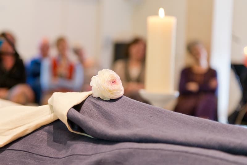 Kaars en gevouwen doek met een roos bij een opbaring