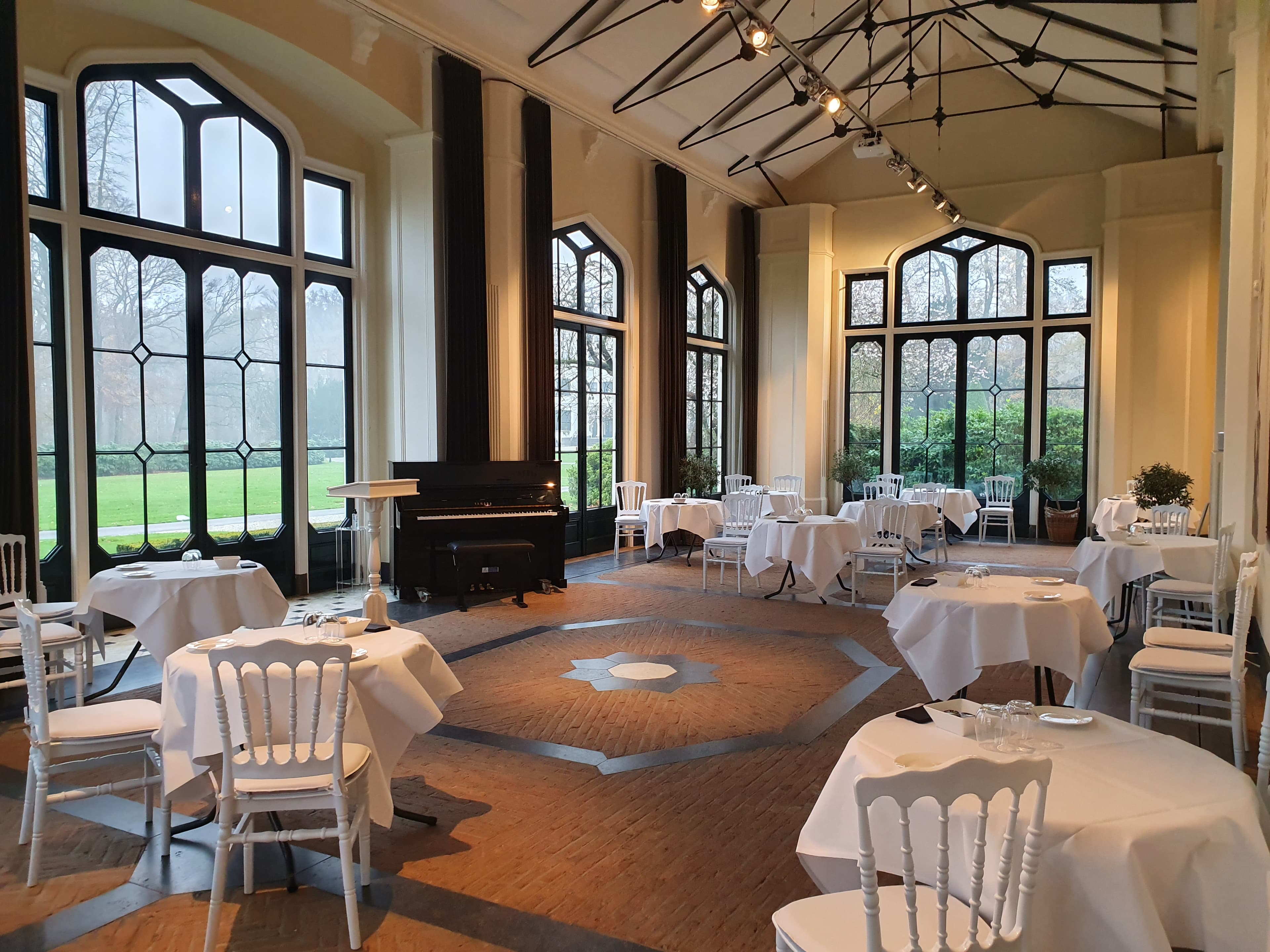 Interieur van Oranjerie Sandenburg met hoge ramen en piano