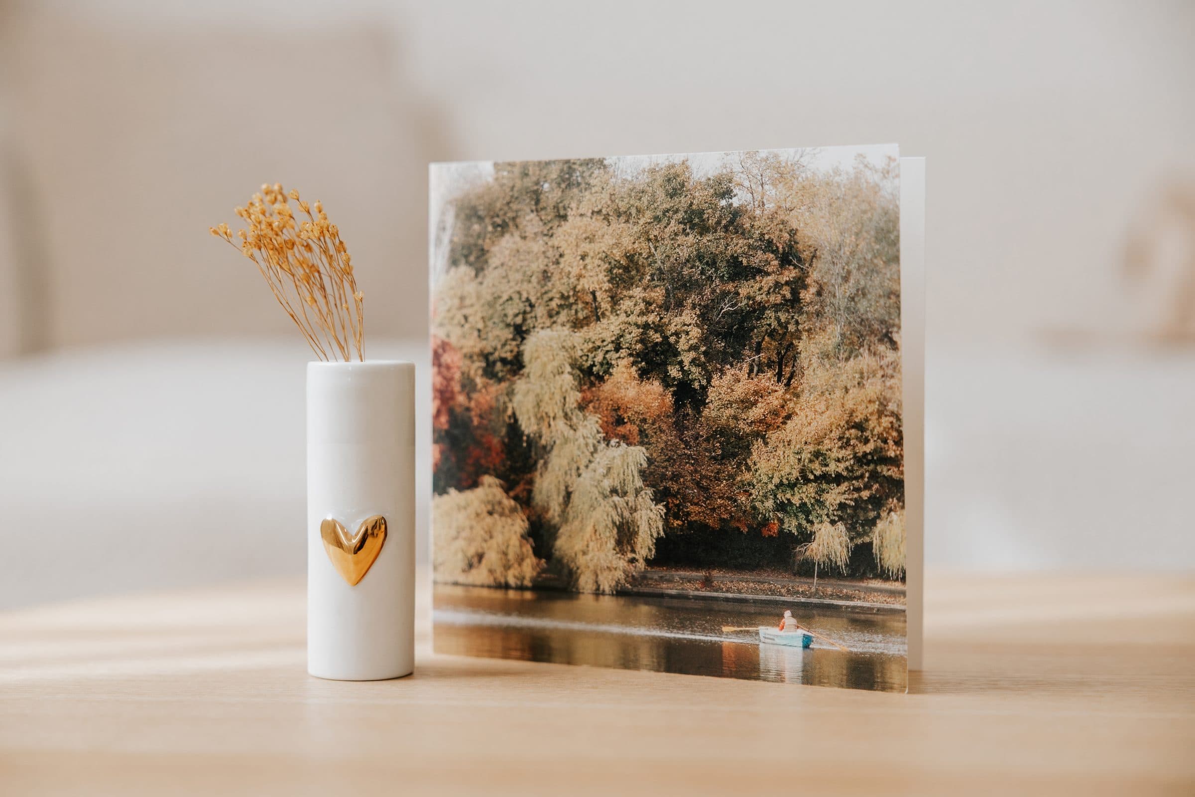 Wit vaasje met gouden hart naast een kaart met herfstbomen