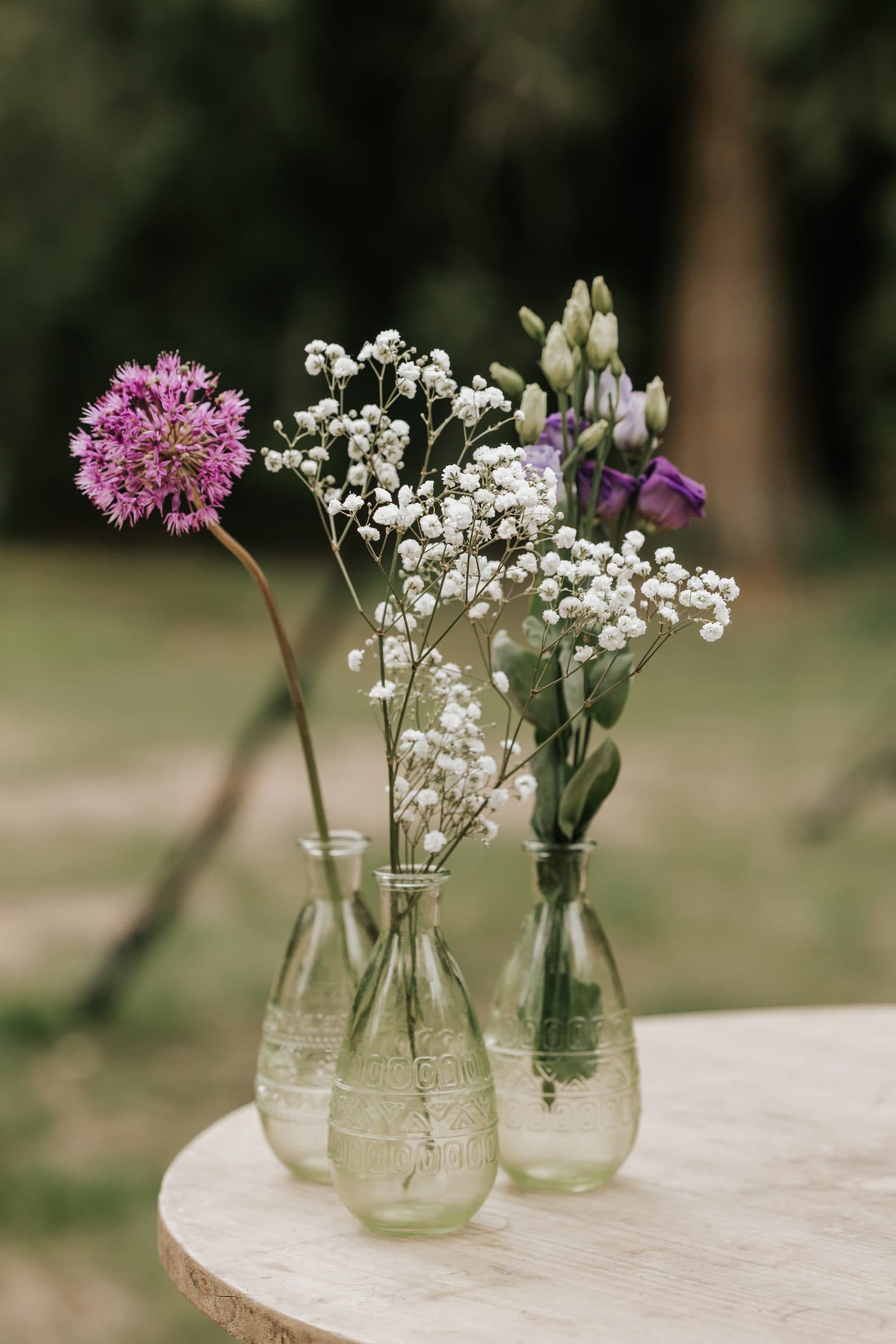 Glazen vaasjes met allium en gipskruid op een tafel