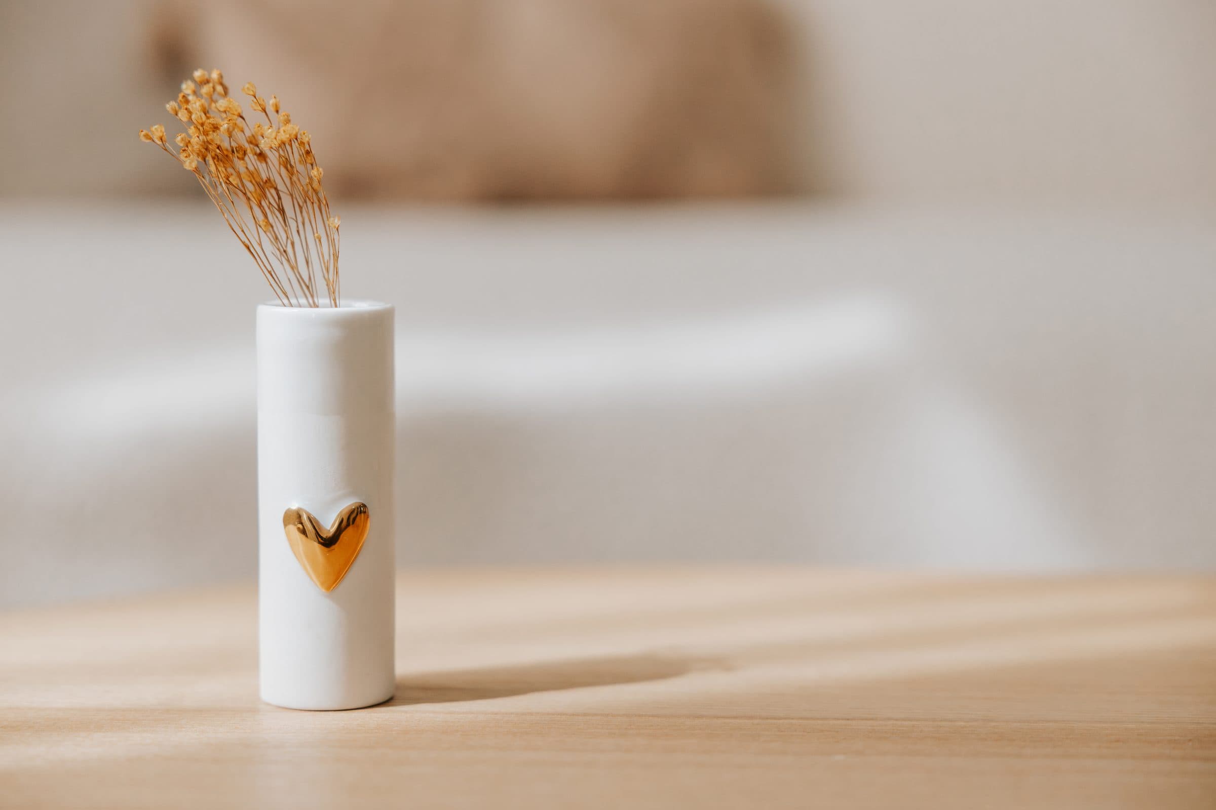 Wit vaasje met een gouden hart en droogbloemen